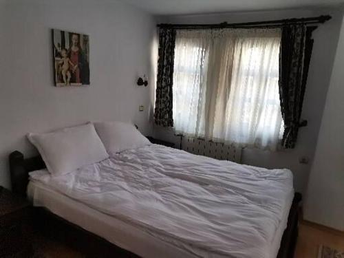 a bedroom with a white bed with a window at Hotel Bolyarka in Melnik