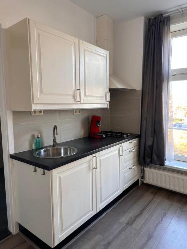 a kitchen with white cabinets and a sink and a window at Studio Wijkhuizen in Zandvoort
