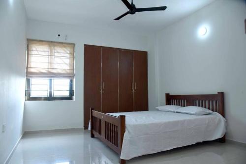 um quarto com uma cama e uma ventoinha de tecto em Krishna Dhwani Apartments em Tellicherry