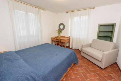 a bedroom with a blue bed and a chair at Agritur La Pieve in Taio