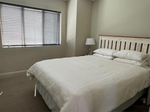 a bedroom with a large white bed with a window at Luxury Townhouse in Stellenbosch CENTRAL (BACK-UP POWER) in Stellenbosch