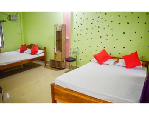 1 dormitorio con 2 camas y almohadas rojas en Hotel Poba, Jonai, Assam, 