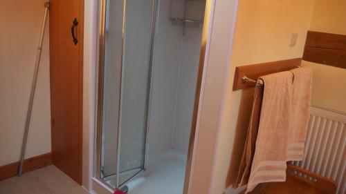 ducha con puerta de cristal y toalla en Hobkin Holiday Cottages, en Broughton in Furness