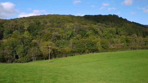un campo verde con una colina al fondo en Hobkin Holiday Cottages, en Broughton in Furness