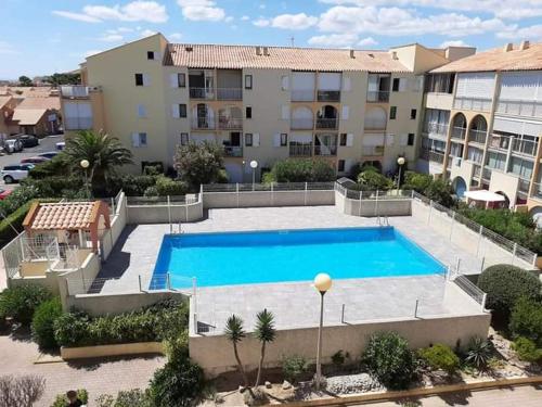 une grande piscine devant un immeuble dans l'établissement T2, rez-de-jardin, terrasse, piscine, Les Maisons de la Plage, Narbonne Plage, à Narbonne-Plage