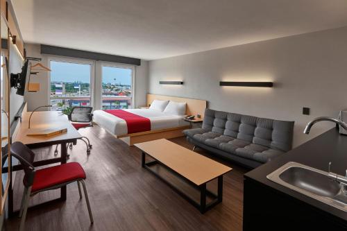 a hotel room with a bed and a couch at City Express by Marriott Tepic in Tepic