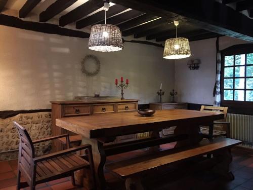a dining room with a wooden table and two lights at chaumière familiale weekend & vacances paisible in Saint-Philbert-sur-Risle