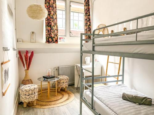 a bedroom with bunk beds and a table and chairs at Hostel ROOM Rotterdam in Rotterdam