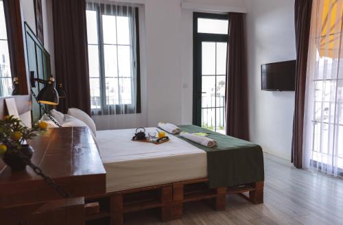 a bedroom with a bed and a table and windows at Limon Inn Hotel, Taşucu in Tasucu