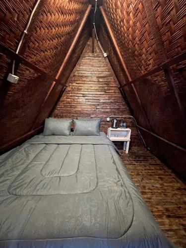 a large bed in a room with a wooden ceiling at Triangular house and hot spring in Kubupenlokan