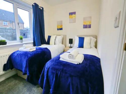 1 dormitorio con 2 camas con sábanas azules y ventana en Pass the Keys King Bed Family Home With Parking WM Discounts, en Mánchester