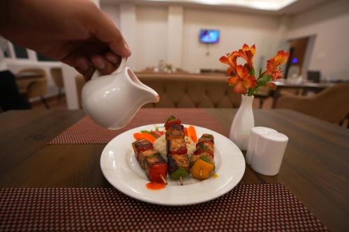 a person pouring a tea pot into a plate of food at Cilantro Comfort in Gangtok