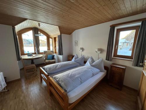 a bedroom with a bed and a desk and windows at Hotel Ristorante Lagrev in Maloja