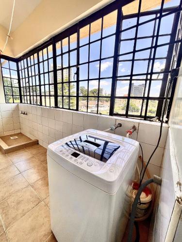 a washing machine in a bathroom with windows at Westlands Escape-Homestay in Nairobi