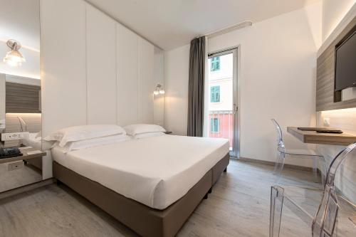 a white bedroom with a large bed and a table at Hotel San Giusto in Trieste