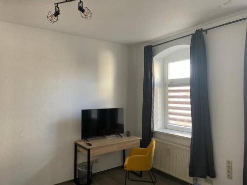 um quarto com uma secretária, uma televisão e uma cadeira amarela em Ferienwohnung 3S Real Estate em Freiberg