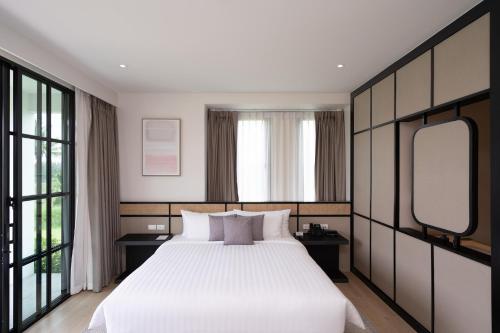 a bedroom with a large white bed with two mirrors at Estella Khao Yai in Khao Yai
