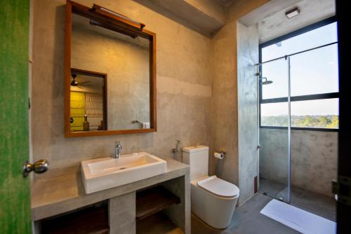 y baño con lavabo, aseo y espejo. en White Moon Hotel, en Gampaha