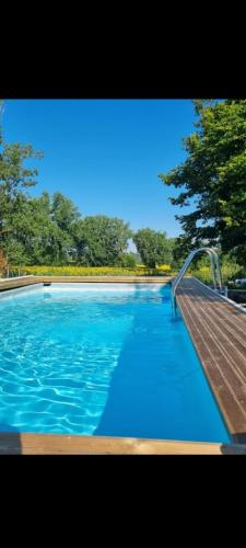 une piscine d'eau bleue et une rampe en bois dans l'établissement Maison de Vacances avec Piscine Privée en Dordogne, à Boisse