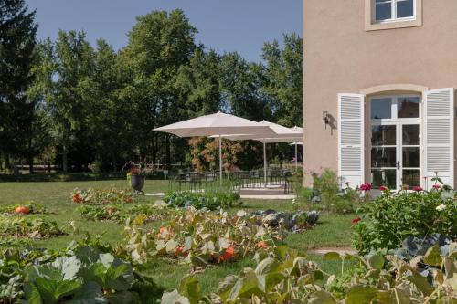 einen Garten vor einem Haus mit Sonnenschirm in der Unterkunft Hôtel Le Prieuré in Paray-le-Monial