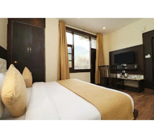 a hotel room with a bed and a television at Hotel Mirage Residency in Dharamshala