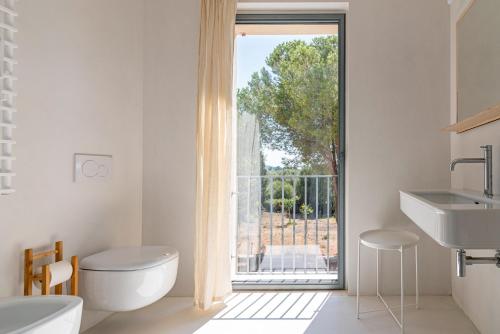 a bathroom with a toilet and a large window at Casale Valverde in Alghero