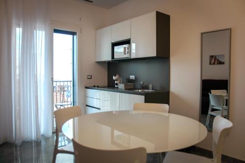 eine Küche und ein Esszimmer mit einem weißen Tisch und Stühlen in der Unterkunft LeTagghjate - Exclusive Rooms and Suites in San Giorgio Ionico