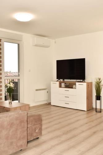 ein weißes Wohnzimmer mit einem Flachbild-TV in der Unterkunft Apartman Biser 4 in Ruma