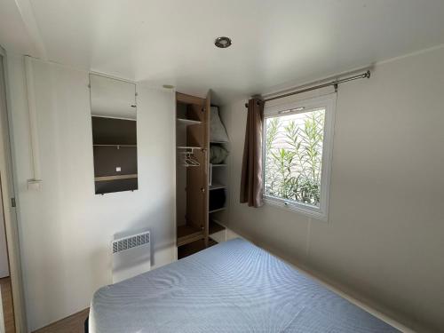 a small bedroom with a bed and a window at Camping Sable du Midi MH 6-8 personnes in Valras-Plage