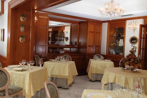 ein Esszimmer mit 2 Tischen und einem Kronleuchter in der Unterkunft Hotel Erika in Fiuggi