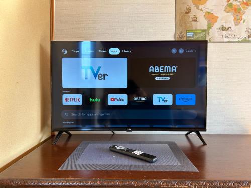 a television with a remote control sitting on a table at Sakura house in Kyoto