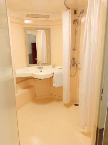 a bathroom with a sink and a mirror and a shower at Premiere Classe Saint Brice Sous Foret in Saint-Brice-sous-For&ecirc;t