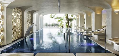 a swimming pool in a hotel with chairs and water at Puente Romano Marbella in Marbella