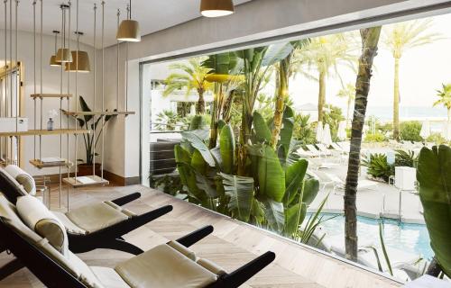 a living room with a large window with chairs and a swimming pool at Puente Romano Marbella in Marbella