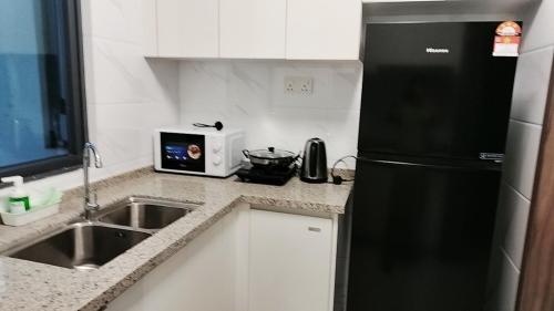a kitchen with a black refrigerator and a sink at 清心小舍03 in Kampong Pok Kechil
