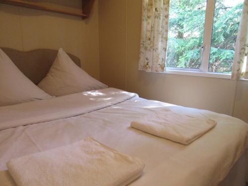 ein weißes Bett mit zwei Handtüchern darüber in der Unterkunft Mobile Home Gorecki in Lidzbark Warmiński