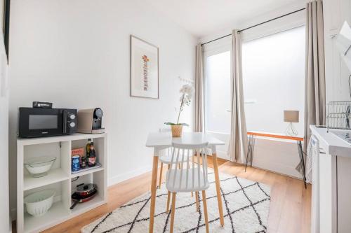 une cuisine avec une table blanche, une table et un tabouret dans l'établissement Le Terminal - Bel appartement quartier Sacré-Coeur, à Bordeaux