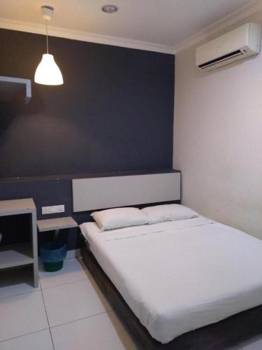 a bedroom with a white bed and a black wall at Hotel Rim Global Pj21 in Kampong Baharu Sungai Way