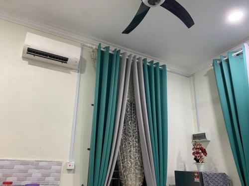 a room with green curtains and a ceiling fan at Homestay Cikgu Fatiah in Kota Bharu