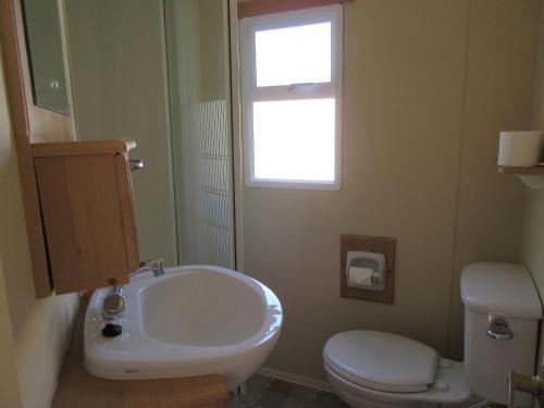 ein Bad mit einem Waschbecken, einem WC und einem Fenster in der Unterkunft Mobile Home Gorecki in Lidzbark Warmiński