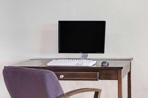 a computer monitor and keyboard on a wooden desk at Days Inn by Wyndham Cocoa Cruiseport West At I-95/524 in Cocoa