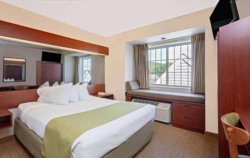 Microtel Inn & Suites by Wyndham Wellsville في Wellsville: غرفة فندقية بسرير كبير ونافذة