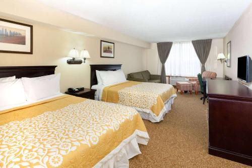 a hotel room with two beds and a desk at Days Inn & Suites by Wyndham Tucker/Northlake in Tucker