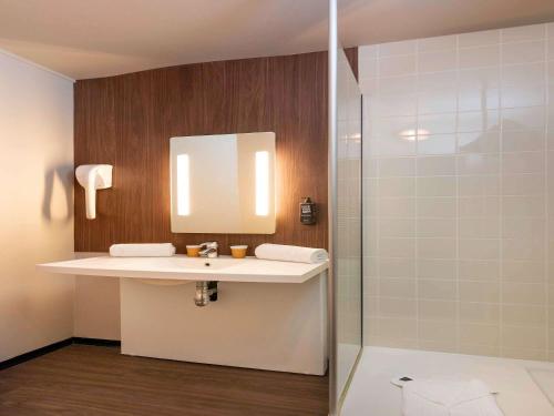La salle de bains est pourvue d'un lavabo et d'une douche. dans l'établissement IBIS STYLES Rouen Parc Expos Zenith, à Saint-Étienne-du-Rouvray