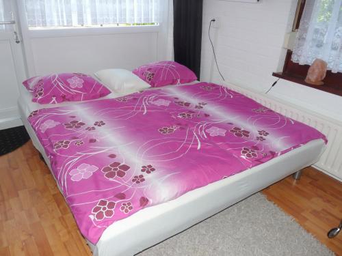 ブルンスムにあるDe Hendrikhoveのピンクの掛け布団が備わるドミトリールームのベッド1台分です。
