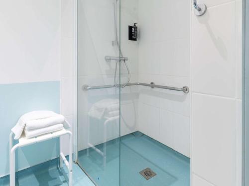 y baño con ducha con puerta de cristal y taburete. en ibis Vesoul, en Vesoul