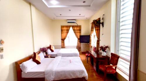 a room with two beds and a table and chairs at Lam Hong Hotel in Xuân Ðài