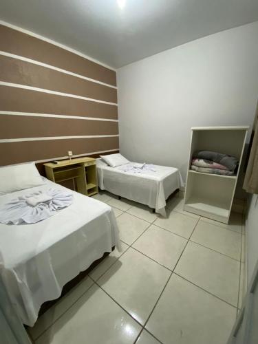 a hotel room with two beds and a tiled floor at Hotel Ferrari in Rio do Sul