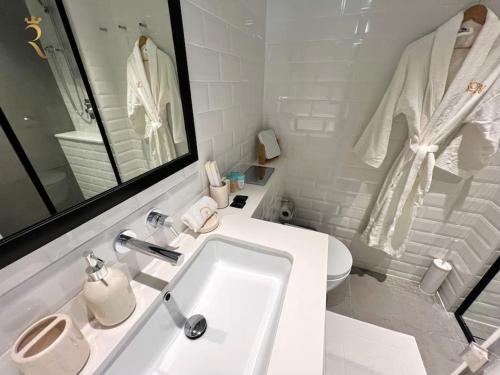 La salle de bains blanche est pourvue d'un lavabo et de toilettes. dans l'établissement 1BR Americana Apartment: Stars and Stripes Haven, à Abu Dhabi