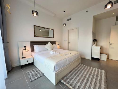1 dormitorio con 1 cama blanca grande y espejo en 1BR Americana Apartment: Stars and Stripes Haven en Abu Dabi